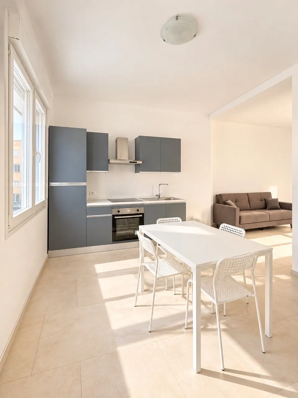 Zona giorno e cucina – Spazio con cucina, tavolo con sedie e divano.