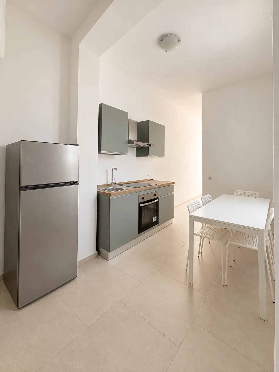Zona cucina – Cucina con frigorifero, piano di lavoro e tavolo.