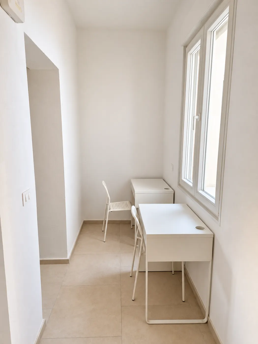 Zona studio – Ambiente con due scrivanie, sedie e finestra.