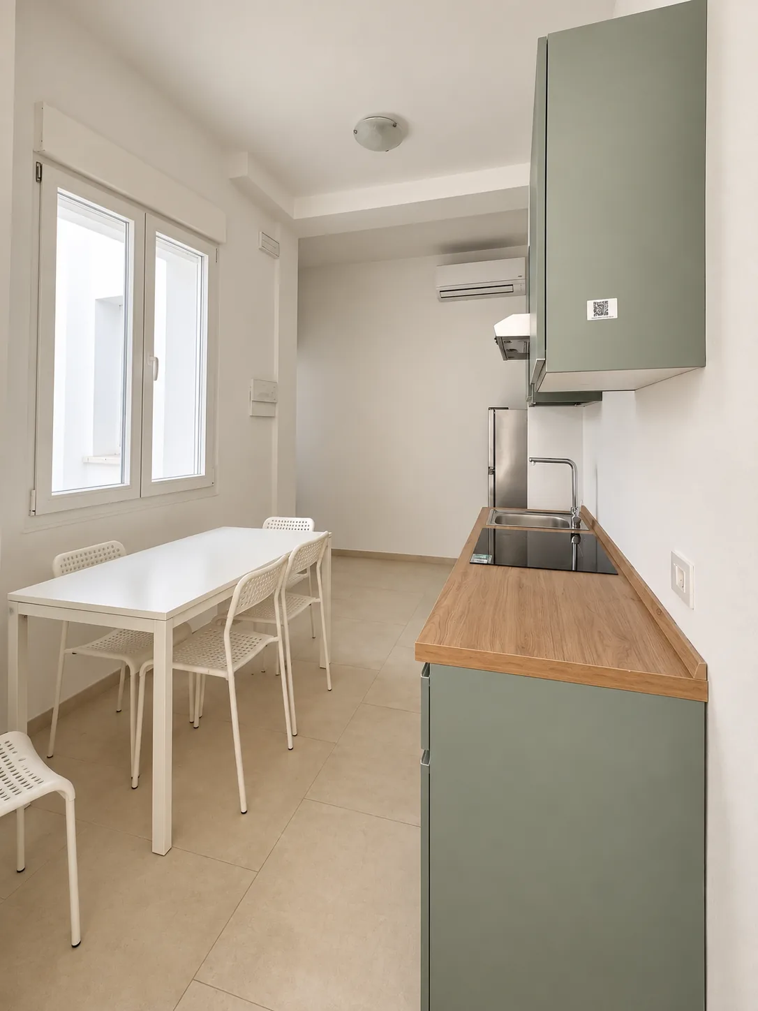 Zona giorno e cucina – Spazio con cucina, tavolo, sedie e finestra.